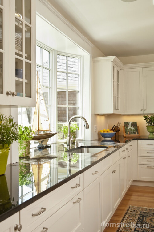 Кухня частного дома с нестандартной, выступающей наружу оконной рамой, которая позволяет увеличить площадь рабочей поверхности подоконника-столешницы