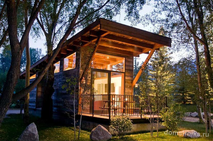 Садовый домик с выступающей крышей, обеспечивающей комфортный отдых на террасе