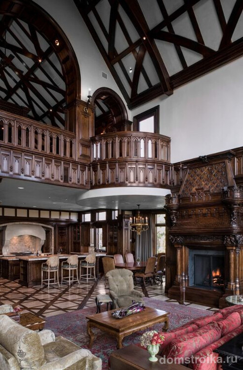 Готическая гостиная украшена резными элементами из темного дерева: перила, камин, стены и даже мебель