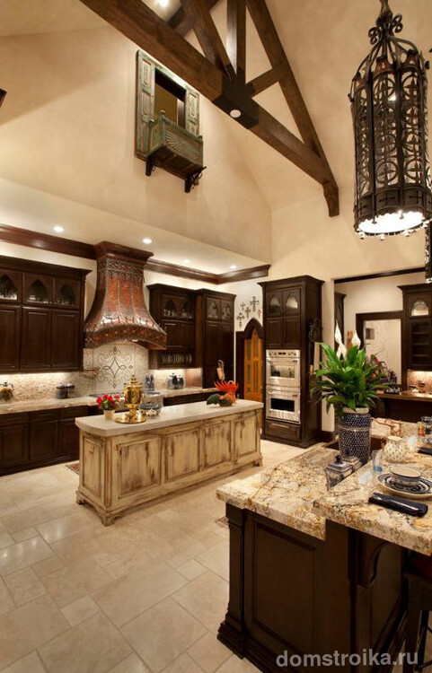 Кухня в готическом стиле: темный гарнитур с мраморной столешницей, точечное освещение зоны готовки и кованный светильник над обеденный зоной
