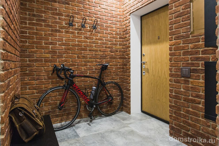 Коридор в стиле лофт с кирпичными стенами и светло-коричневой входной дверью