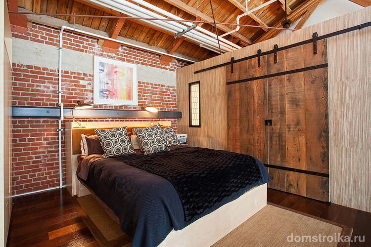 Кирпичная стена и деревянные двери из досок в спальне стиля лофт