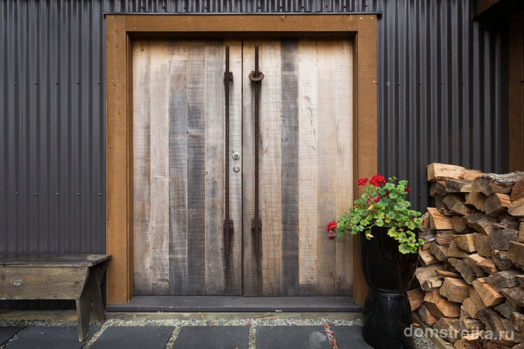 Массивные деревянные входные двери с ручками из металлических прутьев