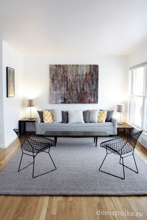 Каркасные кресла, диванные подушки, абстрактное панно над диваном – элементы, контрастирующие с однотонной цветовой гаммой гостиной