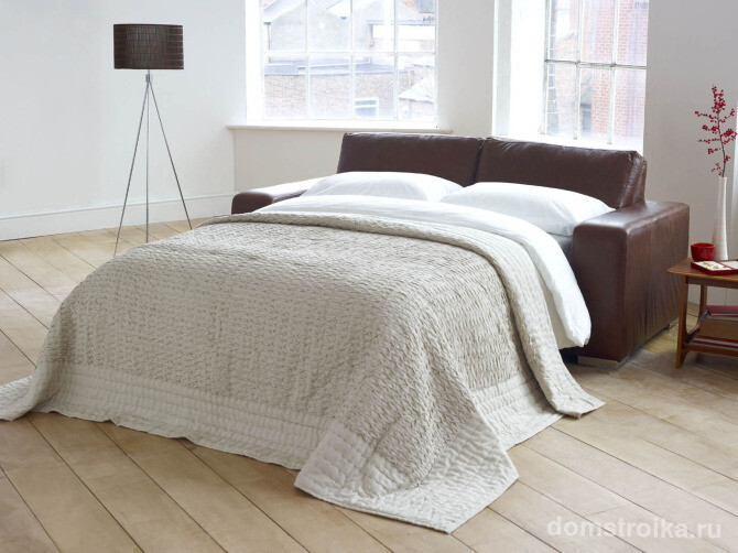 Контрастный кожаный диван в светлой просторной спальне