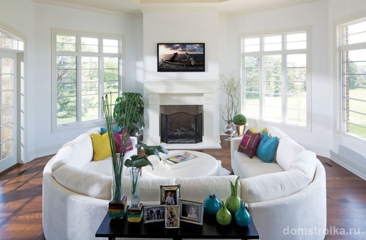 Белый диван, светлые стены, большие окна сделают комнату визуально просторнее