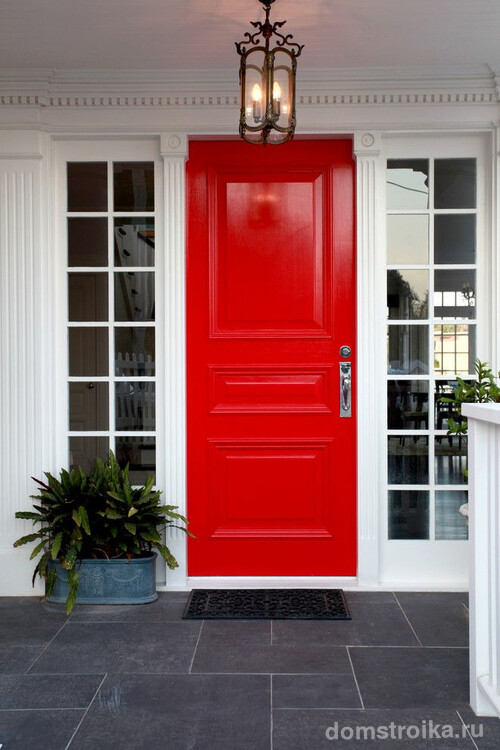 Красивое контрастное сочетание входной двери красного цвета и аккуратных белых пилястр