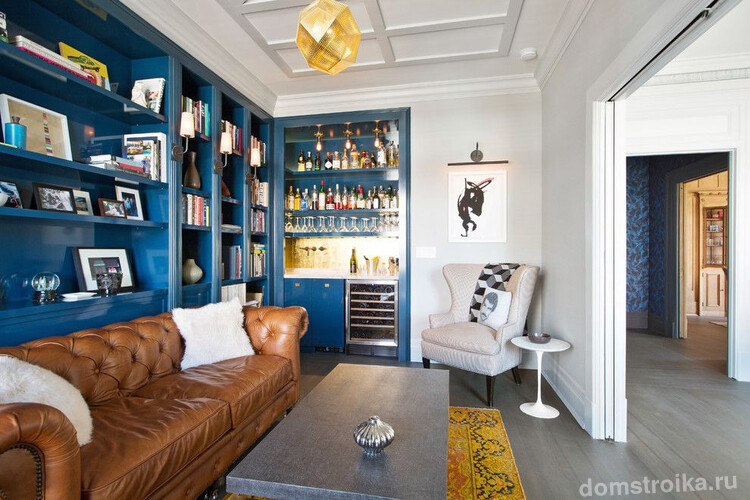 Коричневый кожаный диван хорошо смотрится на фоне синих шкафов