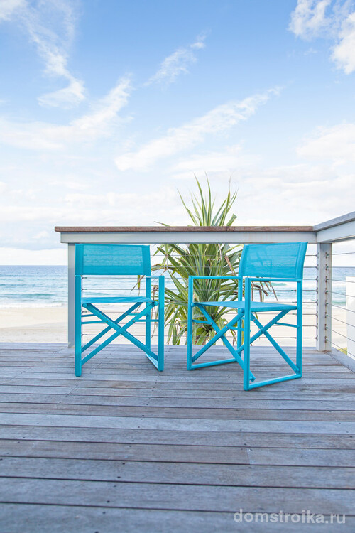 Небольшая терраса с голубыми складными стульями и прекрасным видом на море