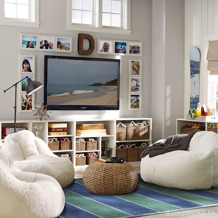 Прекрасный интерьер гостиной в пляжном стиле, где открытая система хранения под телевизором содержится в идеальном порядке с помощью плетеных корзинок