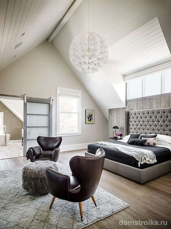 Уютная современная спальня с просторной кроватью и шикарными кожаными креслами