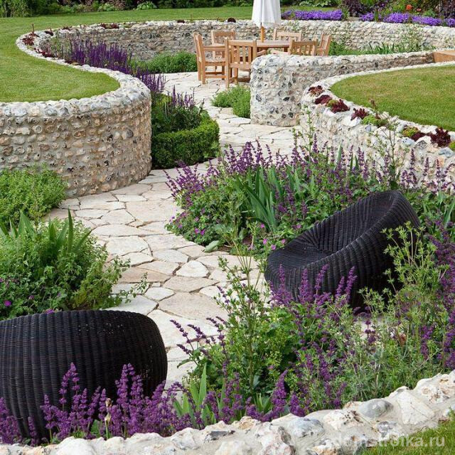 Садовая дорожка и место для отдыха украшено подпорной стеной с отделкой диким камнем