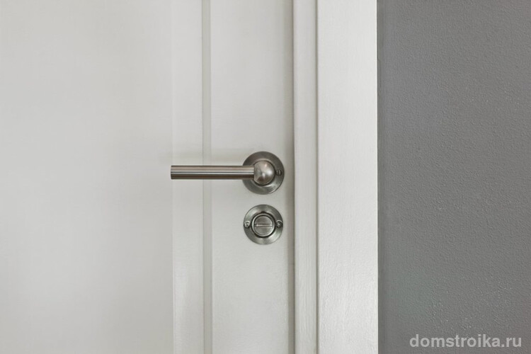 Межкомнатная дверь белого цвета хорошо смотрится с металлической ручкой и замком цвета стали