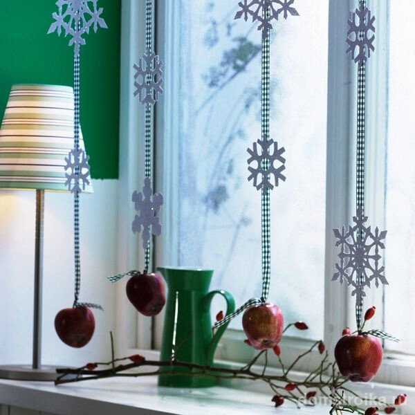 Бумажные снежинки и яблоки на лентах красиво и оригинально украсят зону окна