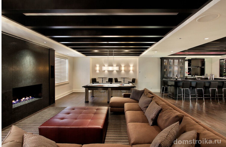 Деревянный потолок и пол дополнены мебелью в коричневых оттенках. Контраст создается за счет точечного освещения и белых стен