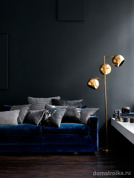Роскошный синит бархат дивана выглядит очень солидно на фоне черной стены. Золотой светильник придает комнате изысканности