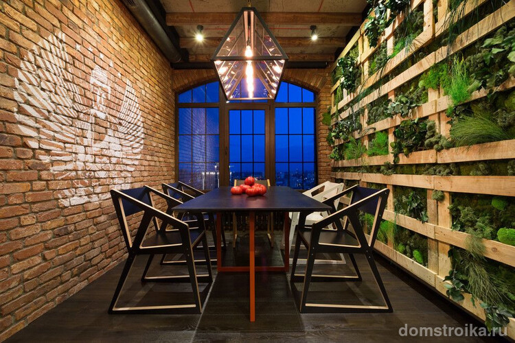 Лаконичная столовая в стиле лофт от группы дизайнеров MARTIN architects: кирпичная стена с противоположной растительной, черный пол, мебель в стиле минимализм, геометрическая осветительная конструкция