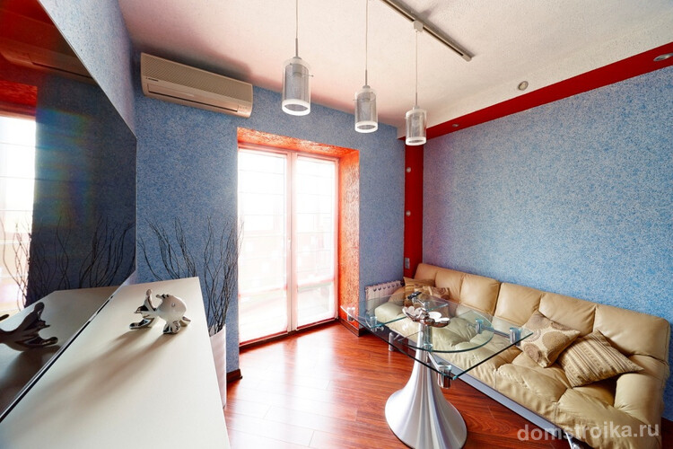 Гармоничное сочетание голубых жидких обоев и красной окантовки в небольшой гостиной