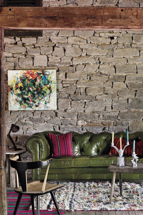 Дикий камень в отделке стены и зеленый "честерфилд" - классические вещи, стильно дополняющие современный интерьер