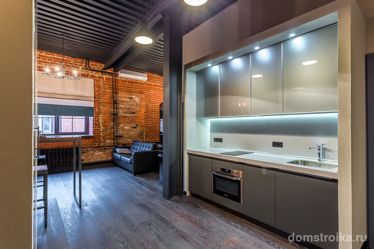 Интересное сочетание гостиной в стиле лофт и современной кухни с глянцевыми шкафами