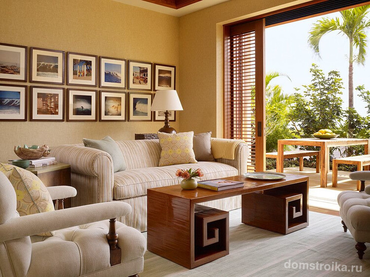 Интерьер комнаты выполнен в светлых бежевых и коричневых тонах. Фотографии вручную наклеены на белую бумагу и обрамлены темно-коричневыми деревянными рамками