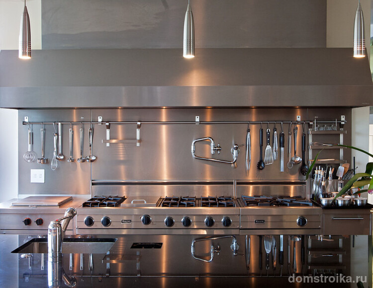 Длинный алюминиевый рейлинг на кухне со шкафами, фартуком и рабочей поверхностью преимущественно из шлифованного металла